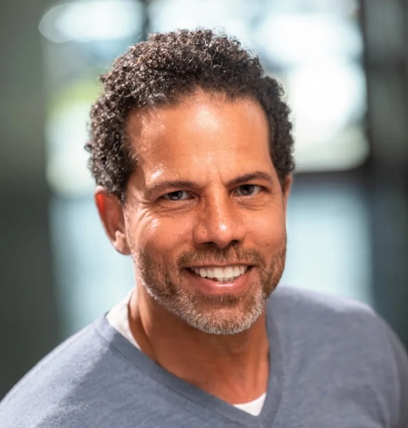 A smiling man with short, defined curls after a men’s curly haircut in Lake Forest, CA